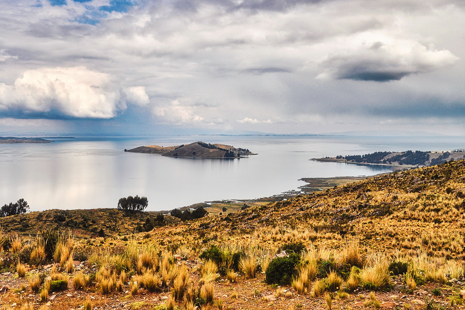Beautiful golden sunset over Lake Titicaca with calm blue waters and distant Andean mountains in Peru