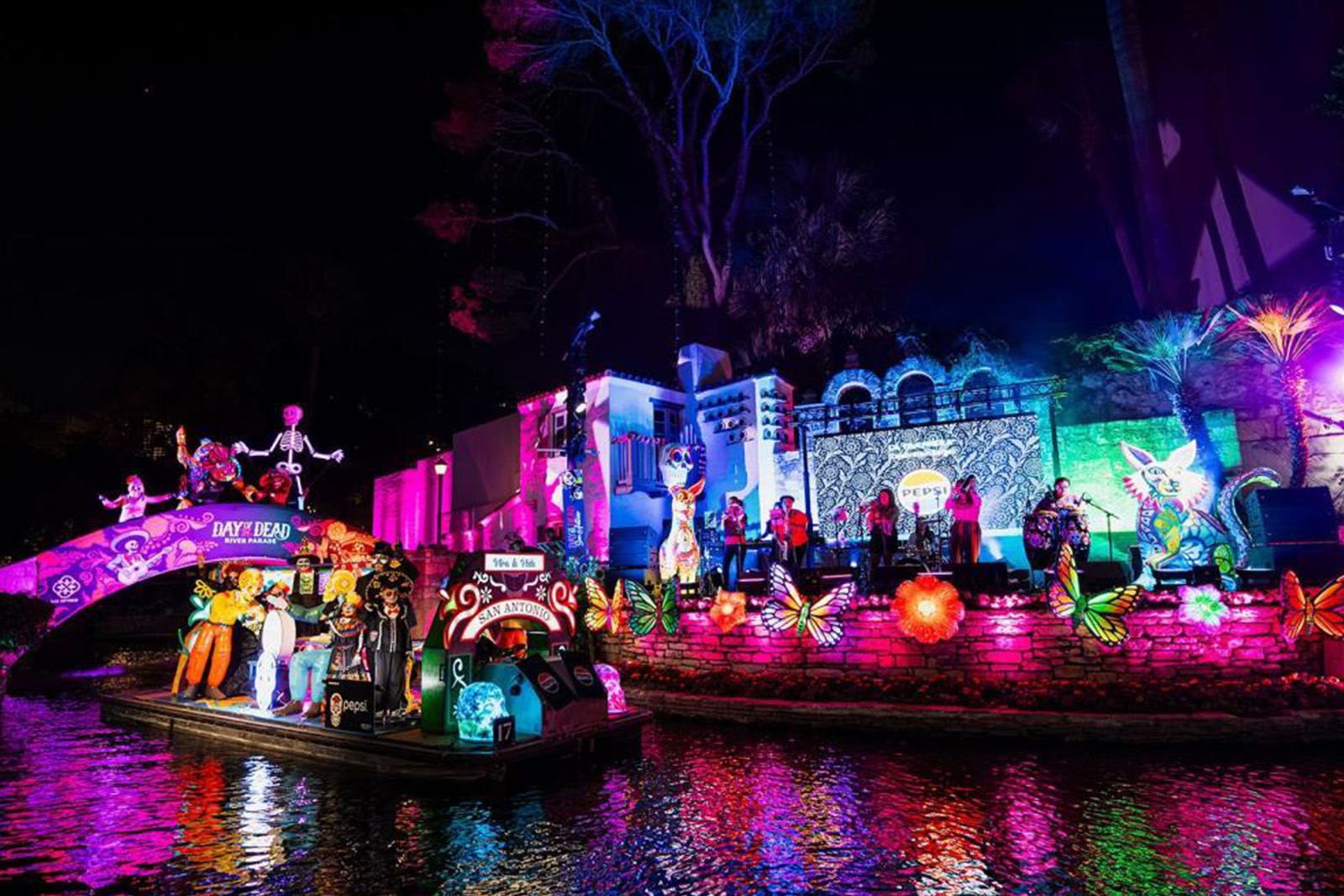 Beautiful San Antonio River Walk illuminated at night with glowing restaurants, colorful lights, scenic bridges and reflections on the water