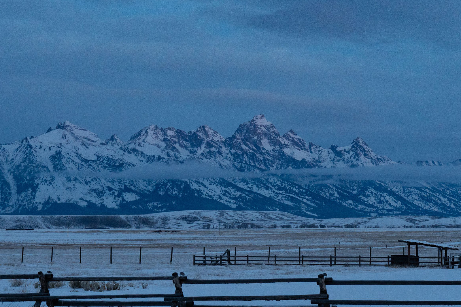 Golden winter sunset illuminating the snow-covered Teton Mountain Range and peaceful Wyoming wilderness